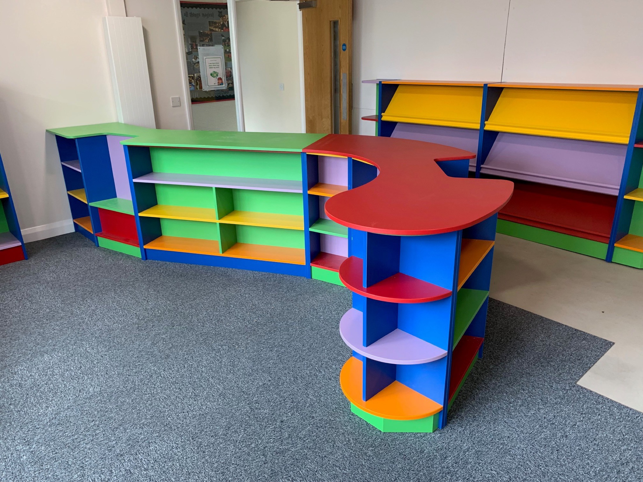 Wide view of colourful school library shelving and display units