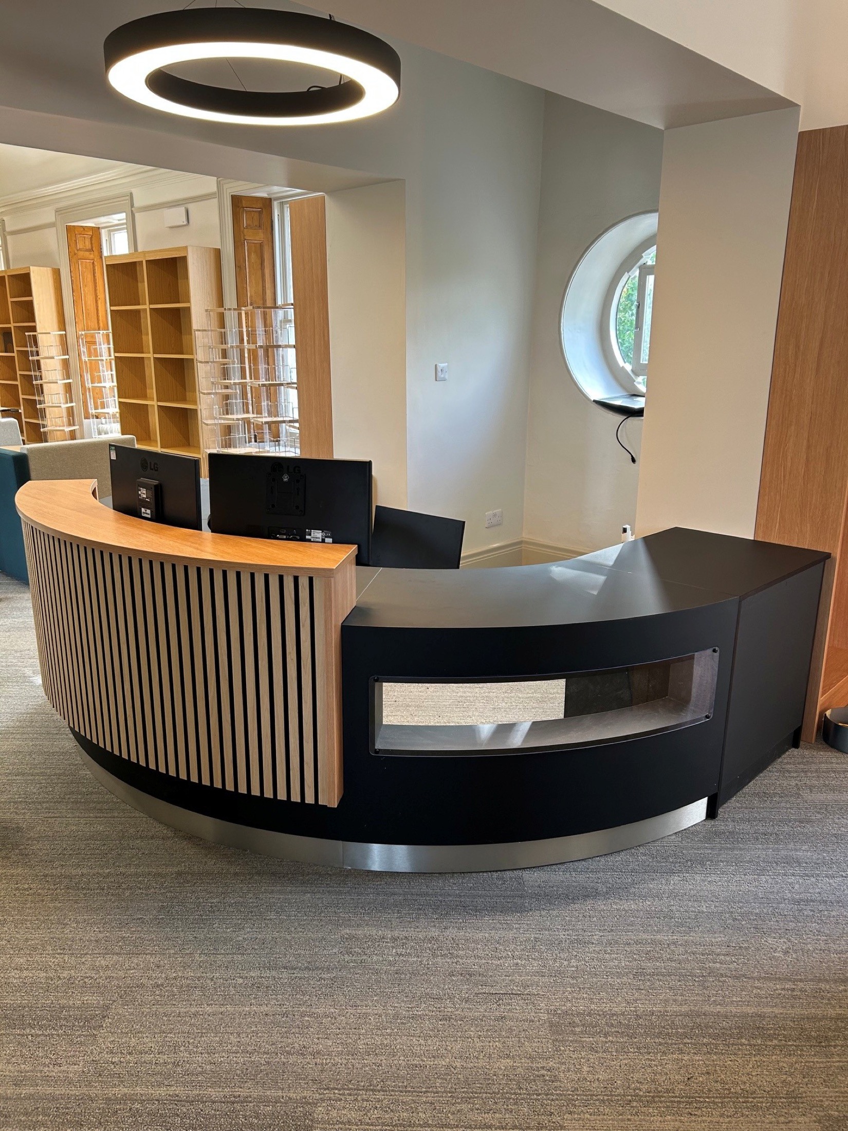 Curved reception desk with timber slat front and black worktop