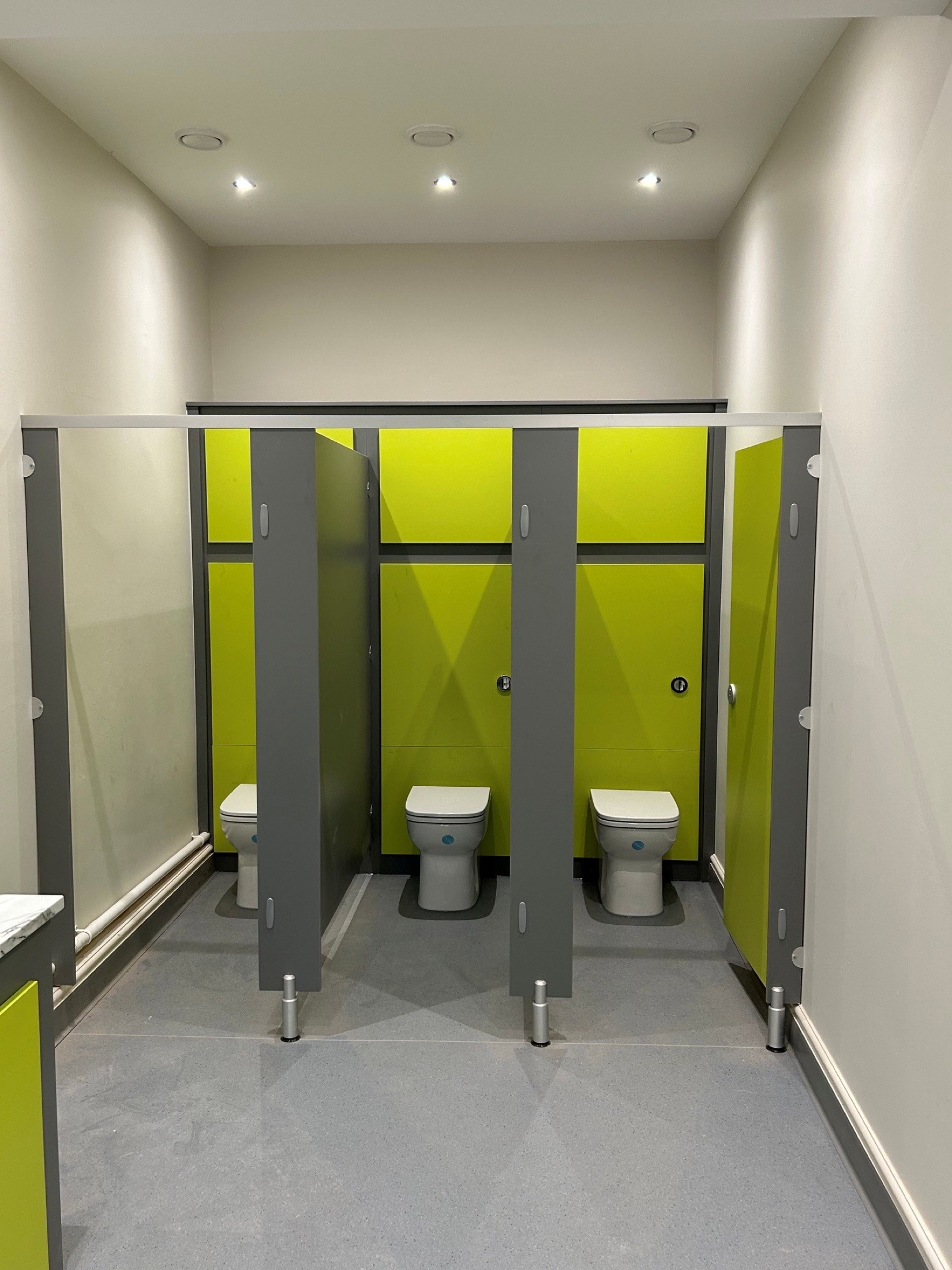 Green and grey toilet cubicles with grey flooring